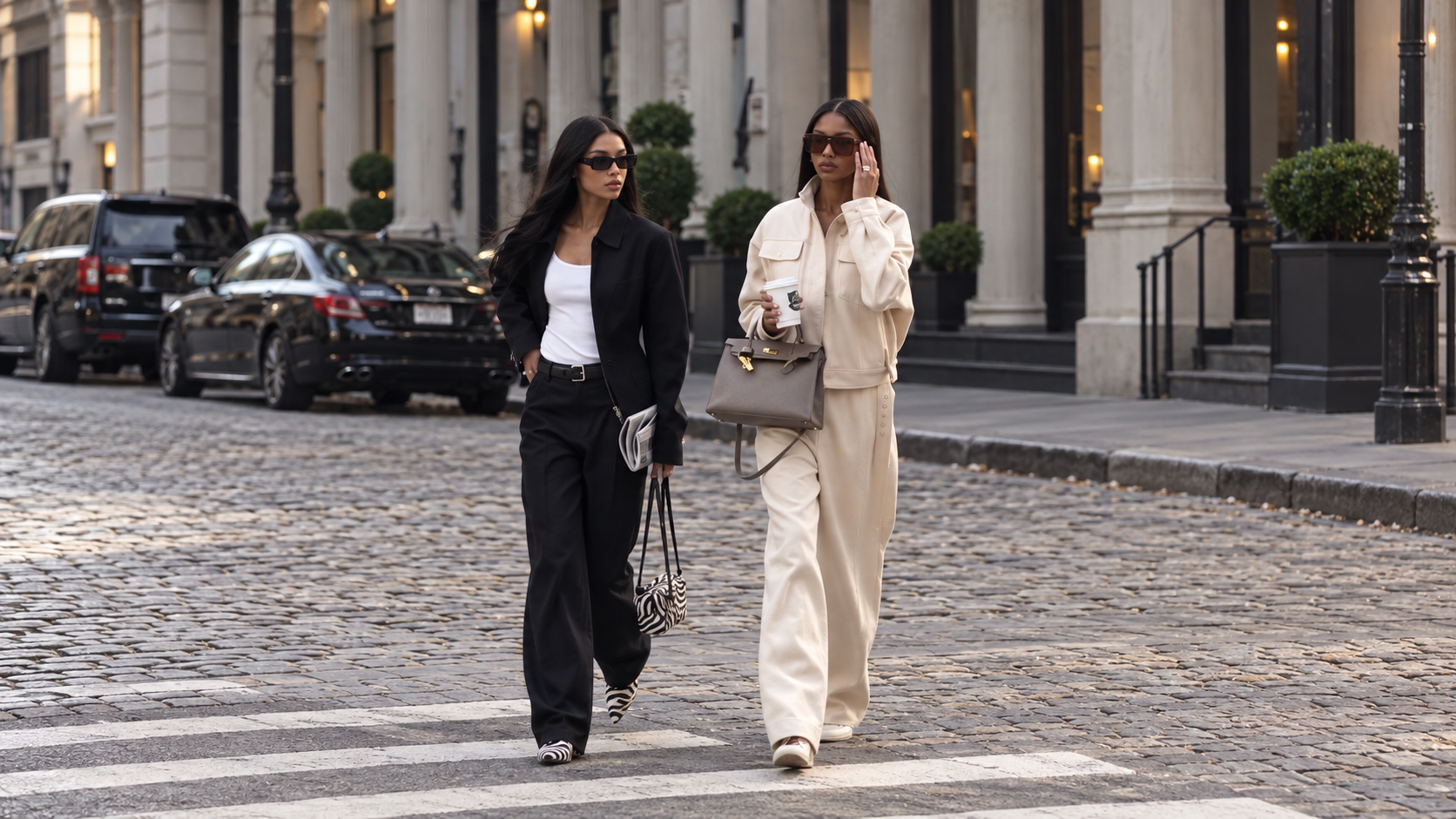 Two fashion creators walking together across a cobblestone city street